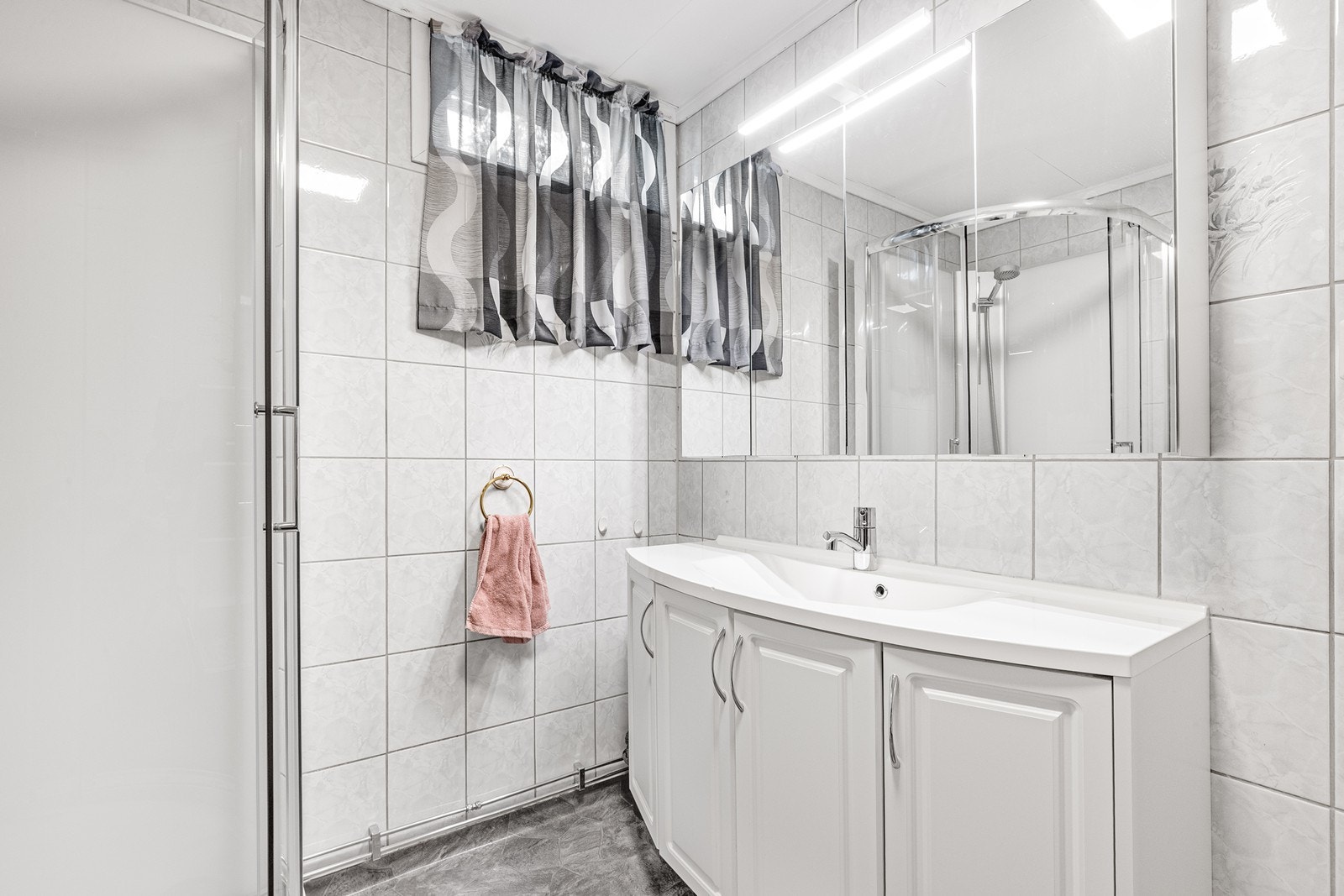 Flislagte vegger og vinylbelegg på gulvet gir badet et funksjonelt preg. Galleribilde
