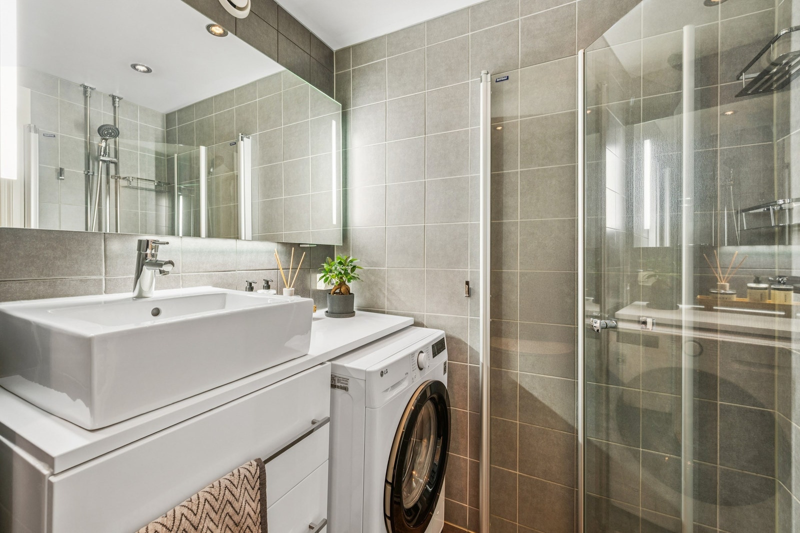 Badet er utstyrt med vegghengt toalett, dusjhjørne med innfellbare dører og opplegg for vaskemaskin. Galleribilde