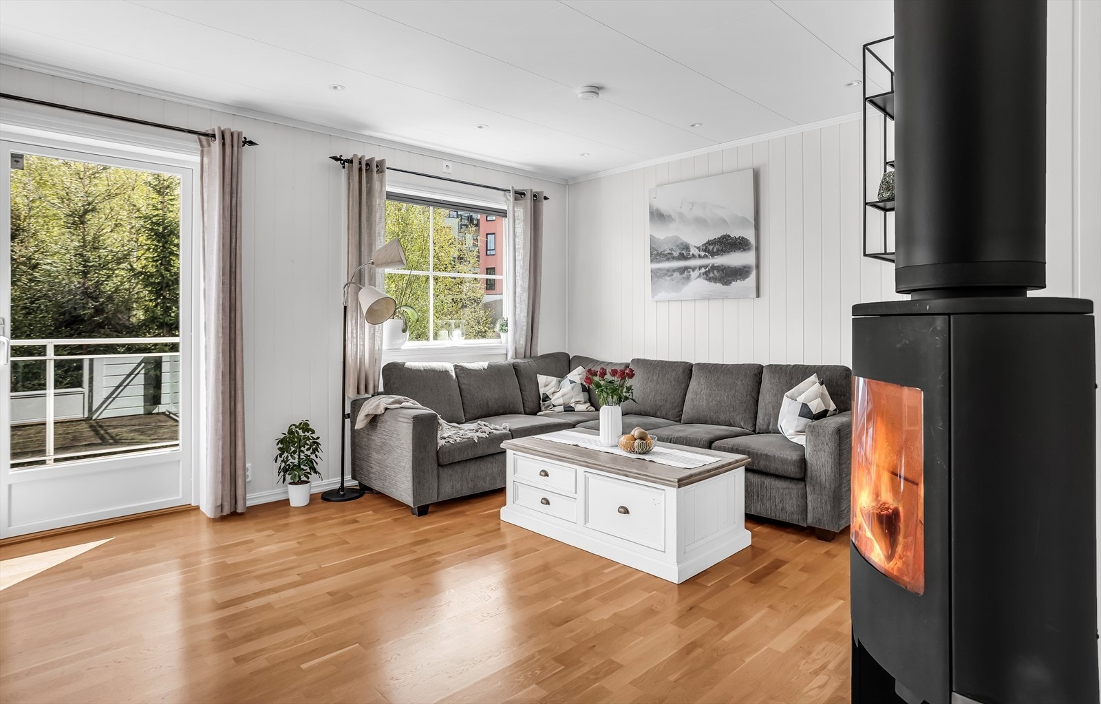 Leiligheten har en åpen og sosial planløsning mellom stue og kjøkken, med en peis som gir varme og atmosfære. Galleribilde