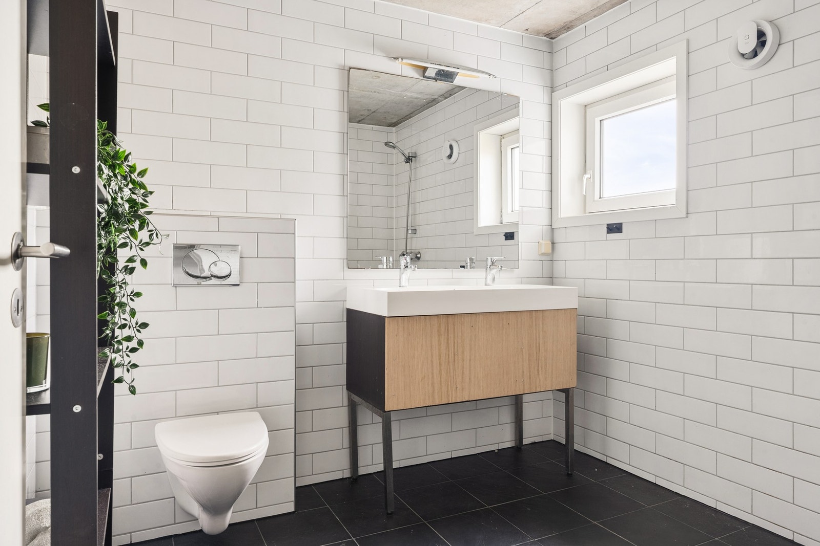 Badet er flislagt og inneholder dusj, toalett og baderomsinnredning Galleribilde