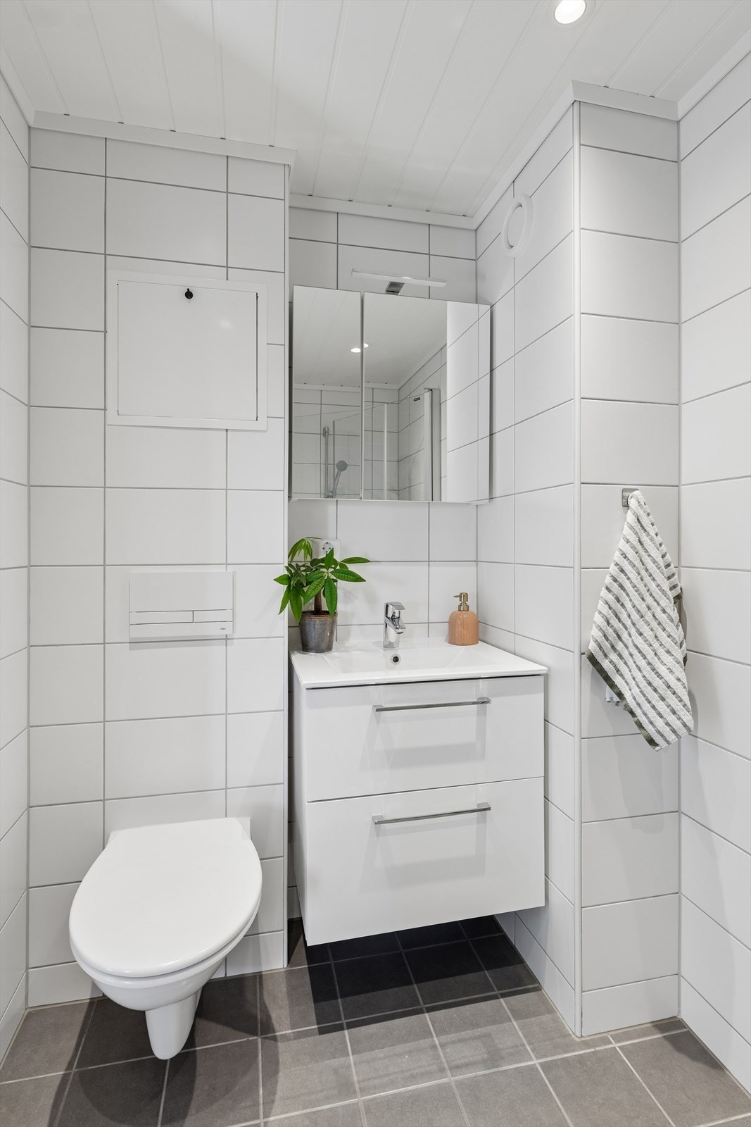 Innredet med servant- og speilskap, vegghengt wc og dusjhjørne. Downlights i himling. Galleribilde