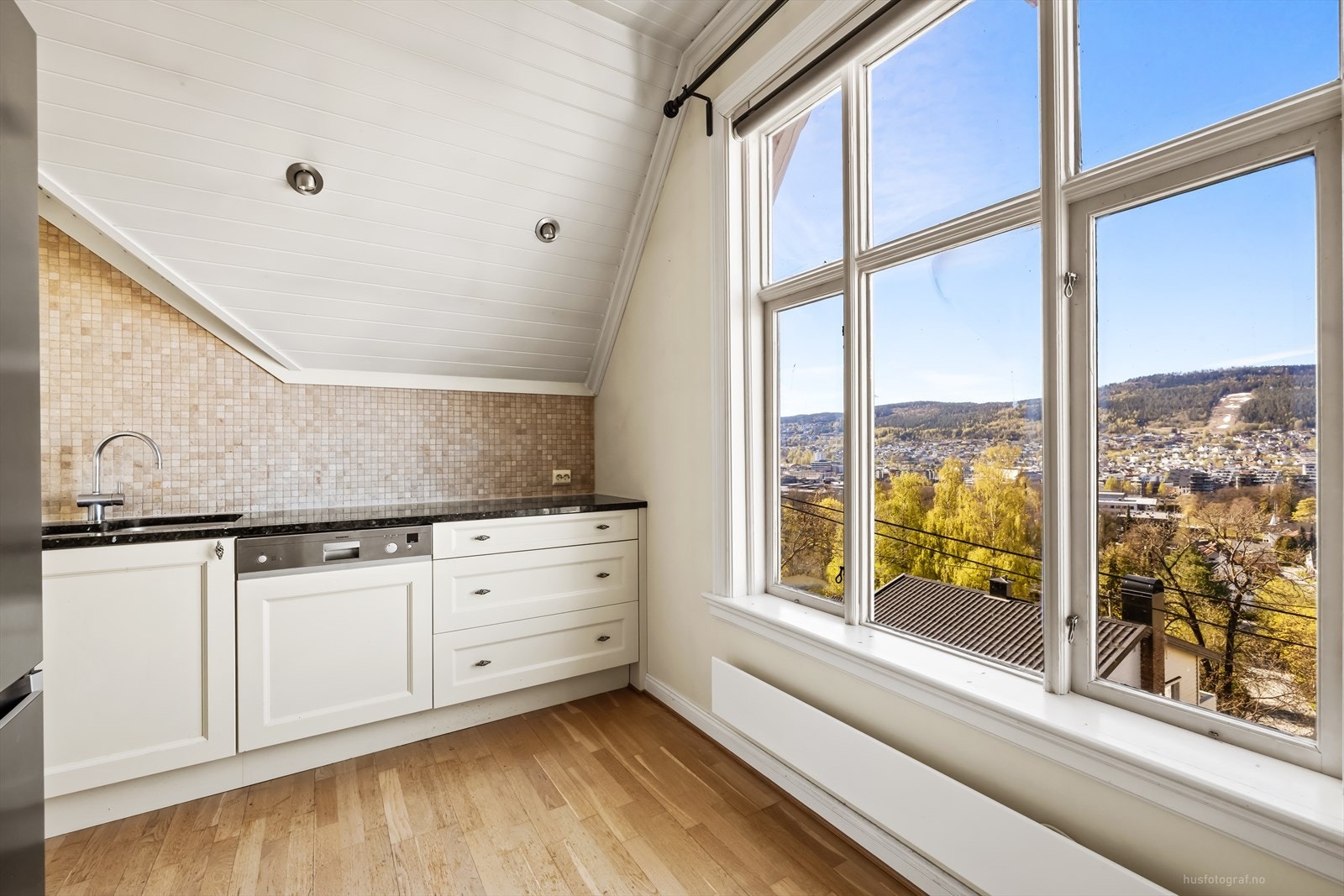 Kjøkkeninnredningen har profilerte fronter og en solid benkeplate i stein. Galleribilde