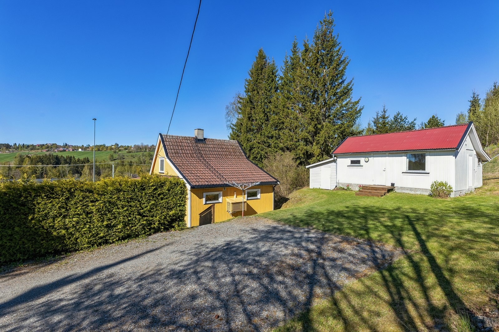 Gruslagt gårdsplass med plass til parkering. På tomten står også et praktisk uthus. Galleribilde
