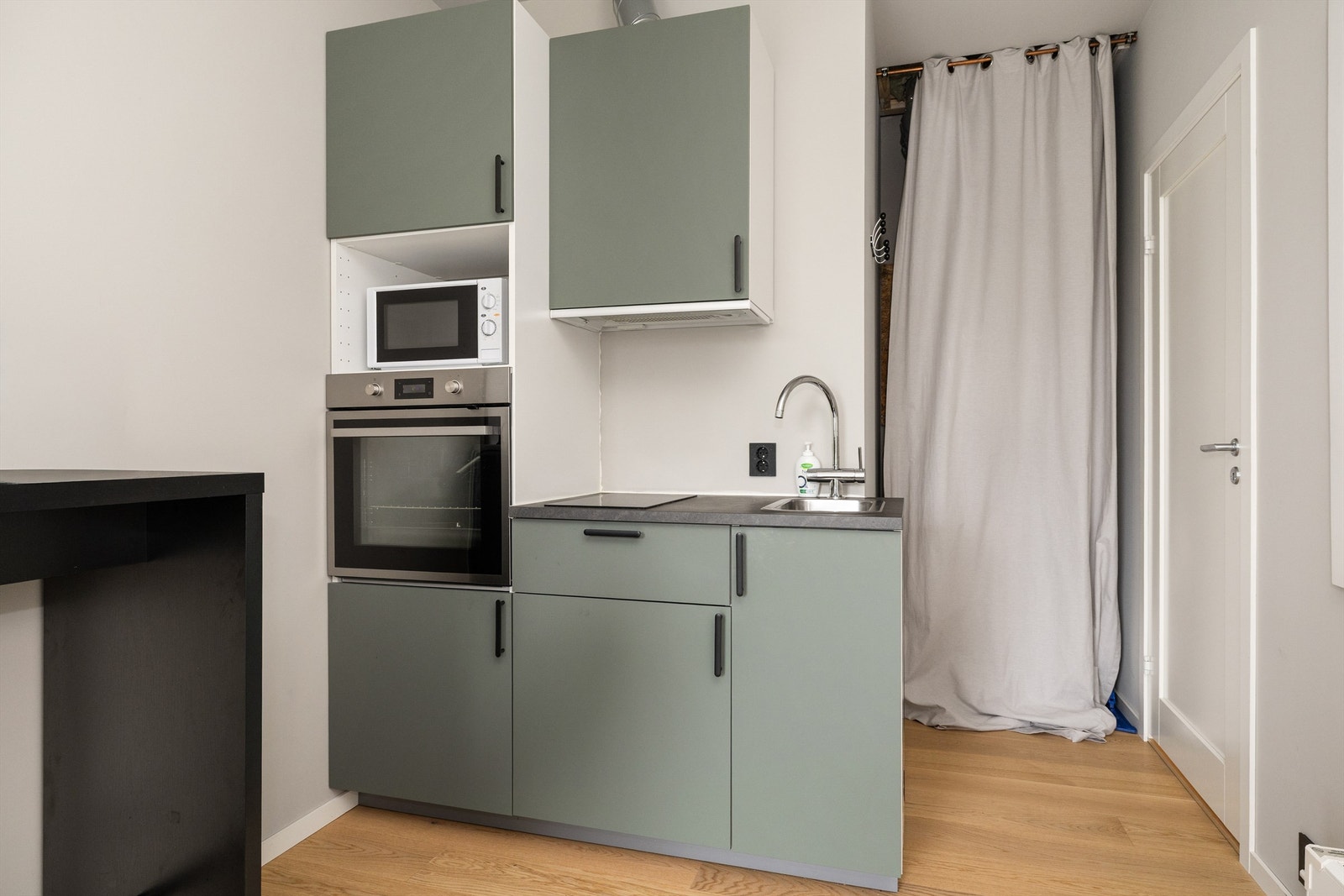 Kjøkkeninnredning fra Ikea i hybel med matte mosegrønne farger og laminat benkeplate Galleribilde