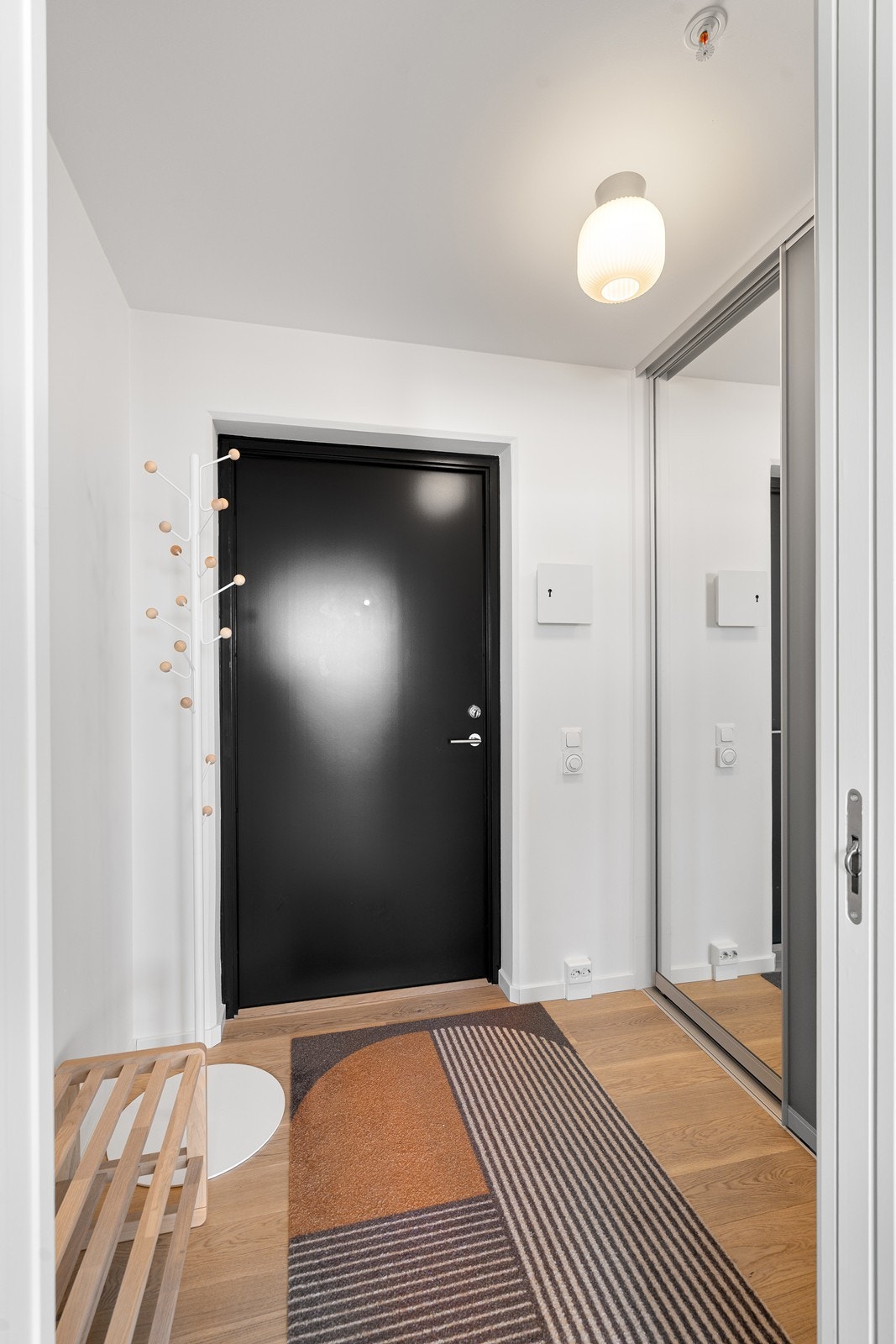 Lys og innbydende entré med praktisk skyvedørsgarderobe med speildører Galleribilde