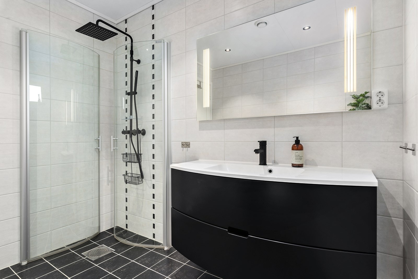 Badet i førsteetasjen har servant med innredning, speil med lys, dusjhjørne med innfellbare dører og vegghengt wc. Galleribilde