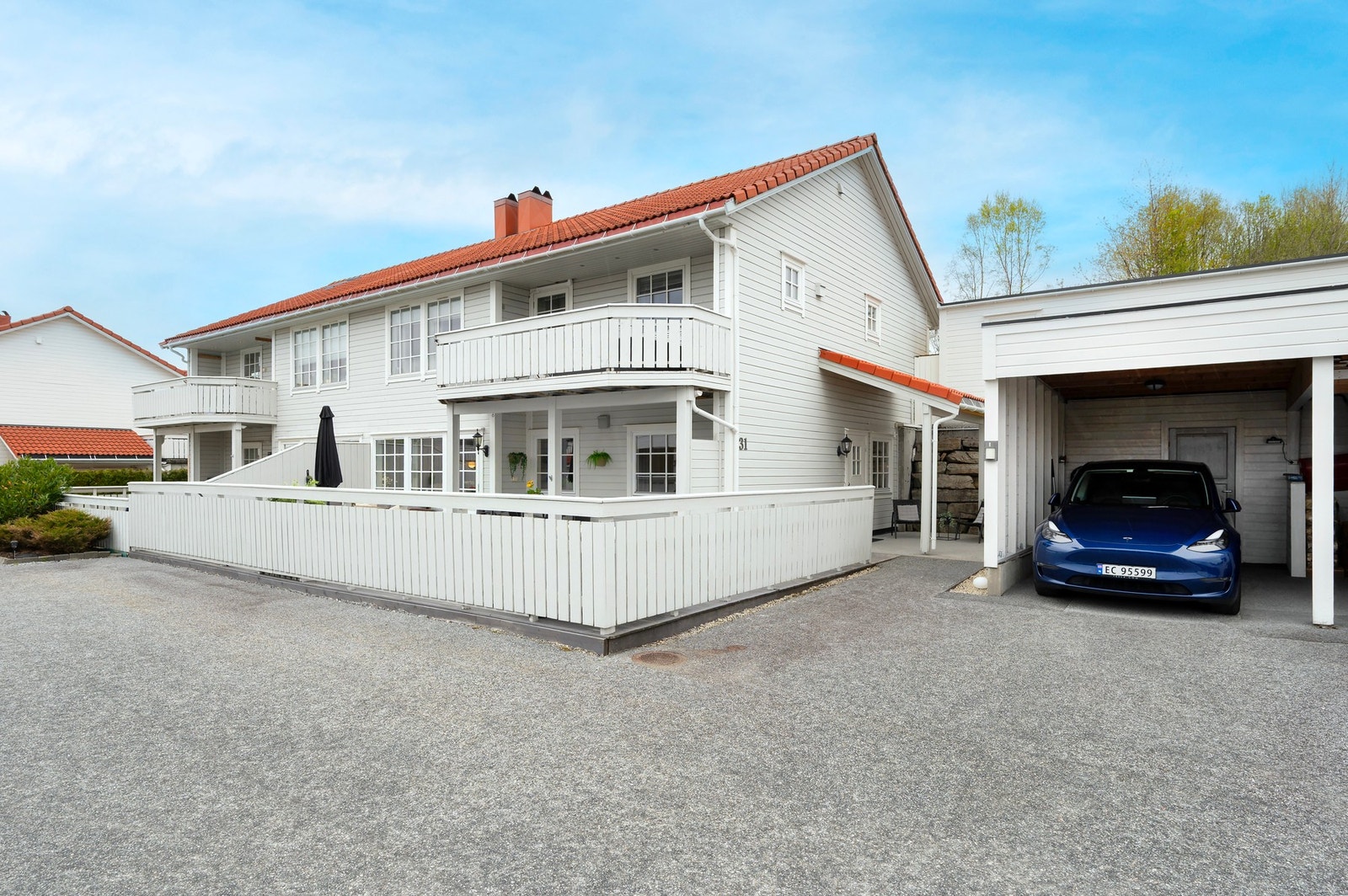 Carport like ved inngangspartiet med elbil-lader og en bod i bakkant. Galleribilde