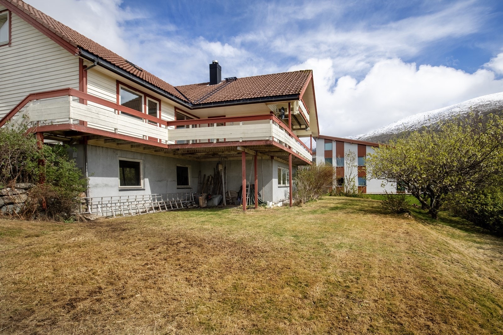Skrånende, sydvendt flat og terrassert tomt på 755,8 m² er opparbeidet med betongplattinger, -trapper, forstøtningsmurer, treterrasse, belegningsstein, skiferheller, frukttrær, plen og beplantning Galleribilde