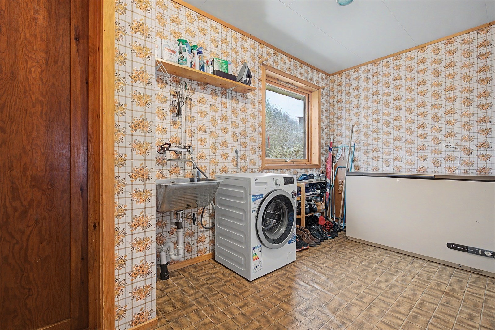 Vaskerom i hovedetasjen har vinylbelegg på gulv og vinyltapet på vegger | rommet er utstyrt med skyllekar og røropplegg for vaskemaskin Galleribilde