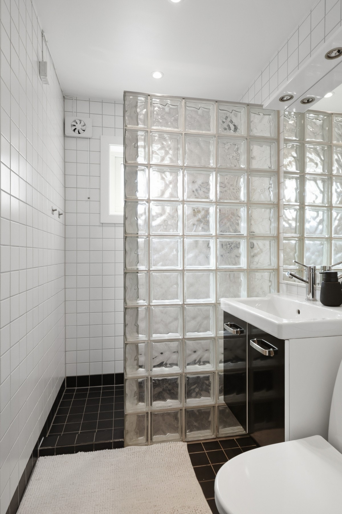 Badet er innredet med hvite veggfliser og sorte gulvfliser for en fin kontrast Galleribilde