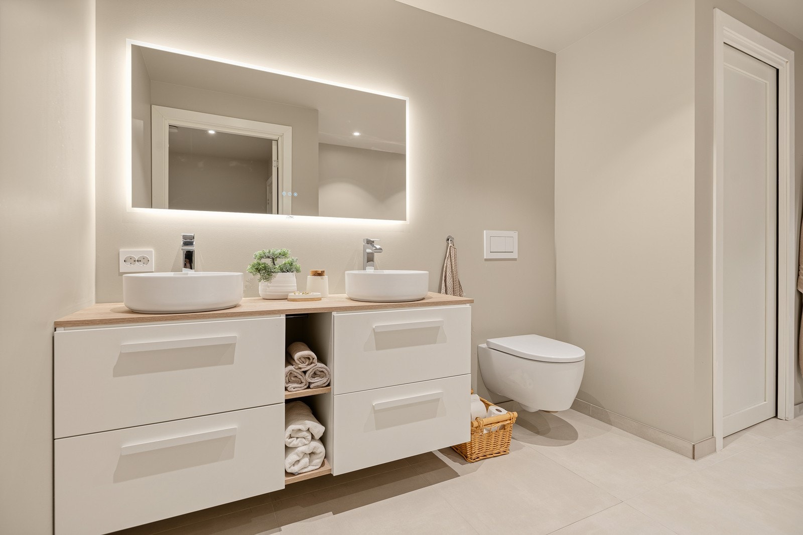 Badet fremstår svært lekkert med delikate, beige fliser, varmekabler i gulv og stilren innredning som gir en lun og moderne helhet Galleribilde