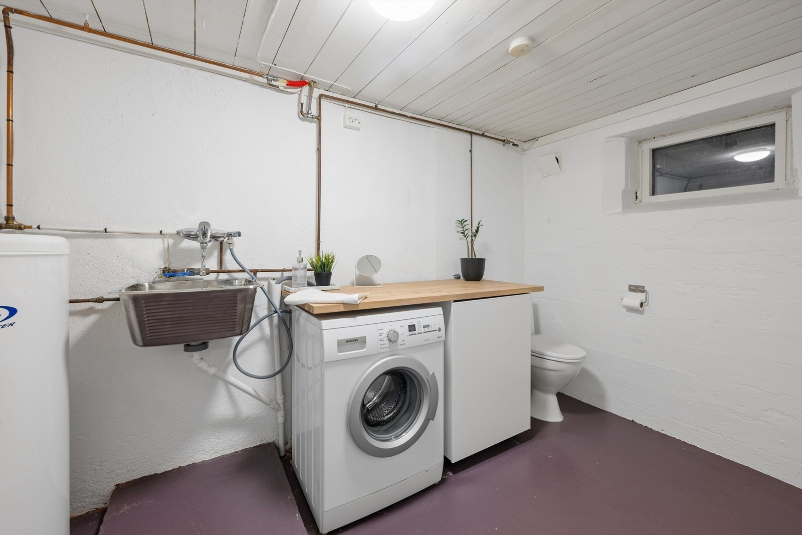 Praktisk vaskerom i kjelleren med toalett, utslagsvask og opplegg for vaskemaskin. Galleribilde