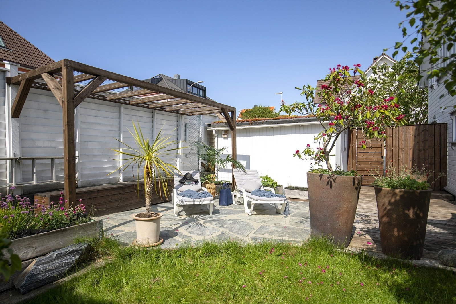 En usjenert del av uteområdet med steinheller og pergola. Galleribilde