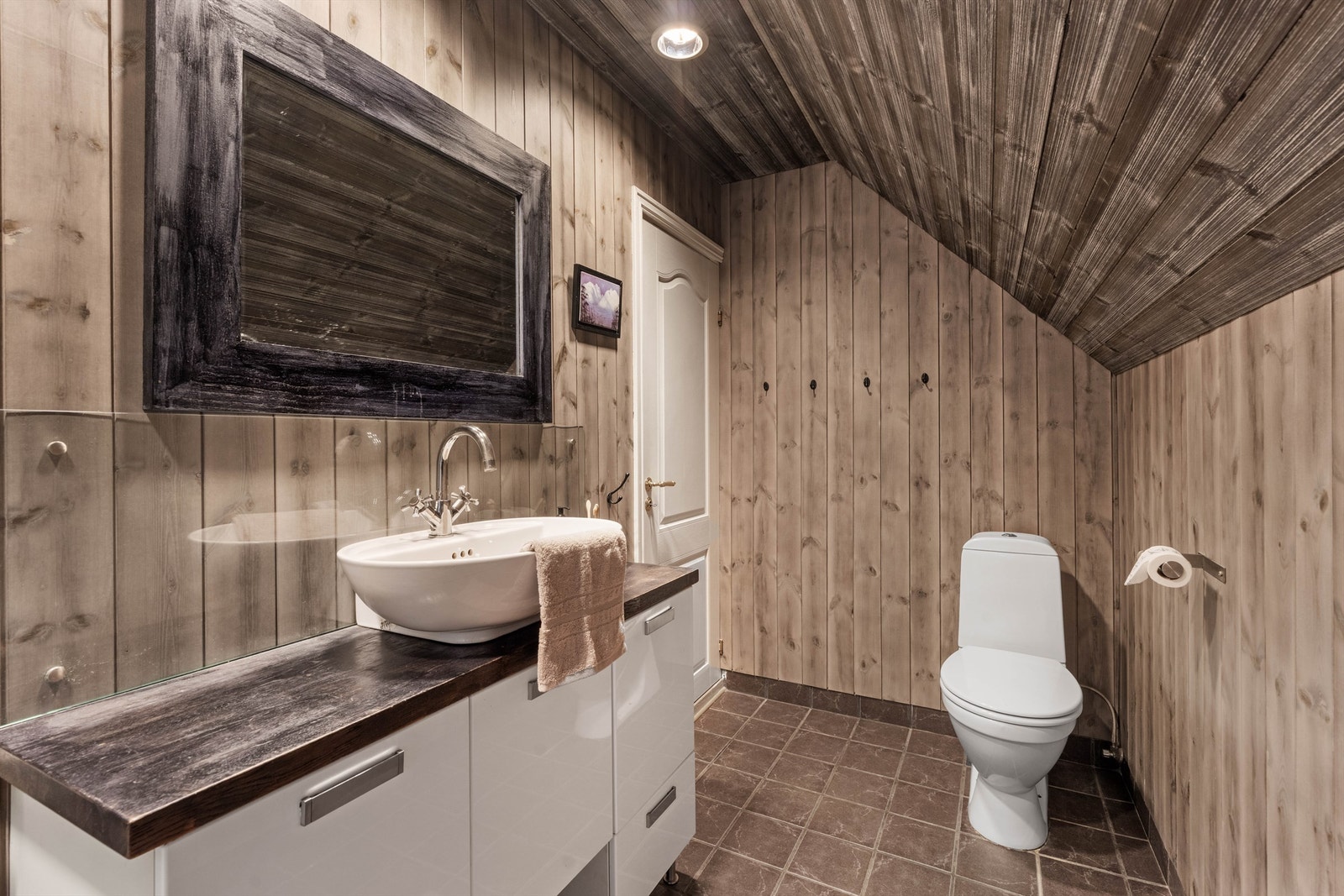 Badet er utstyrt med servantinnredning, toalett og dusjkabinett. Galleribilde