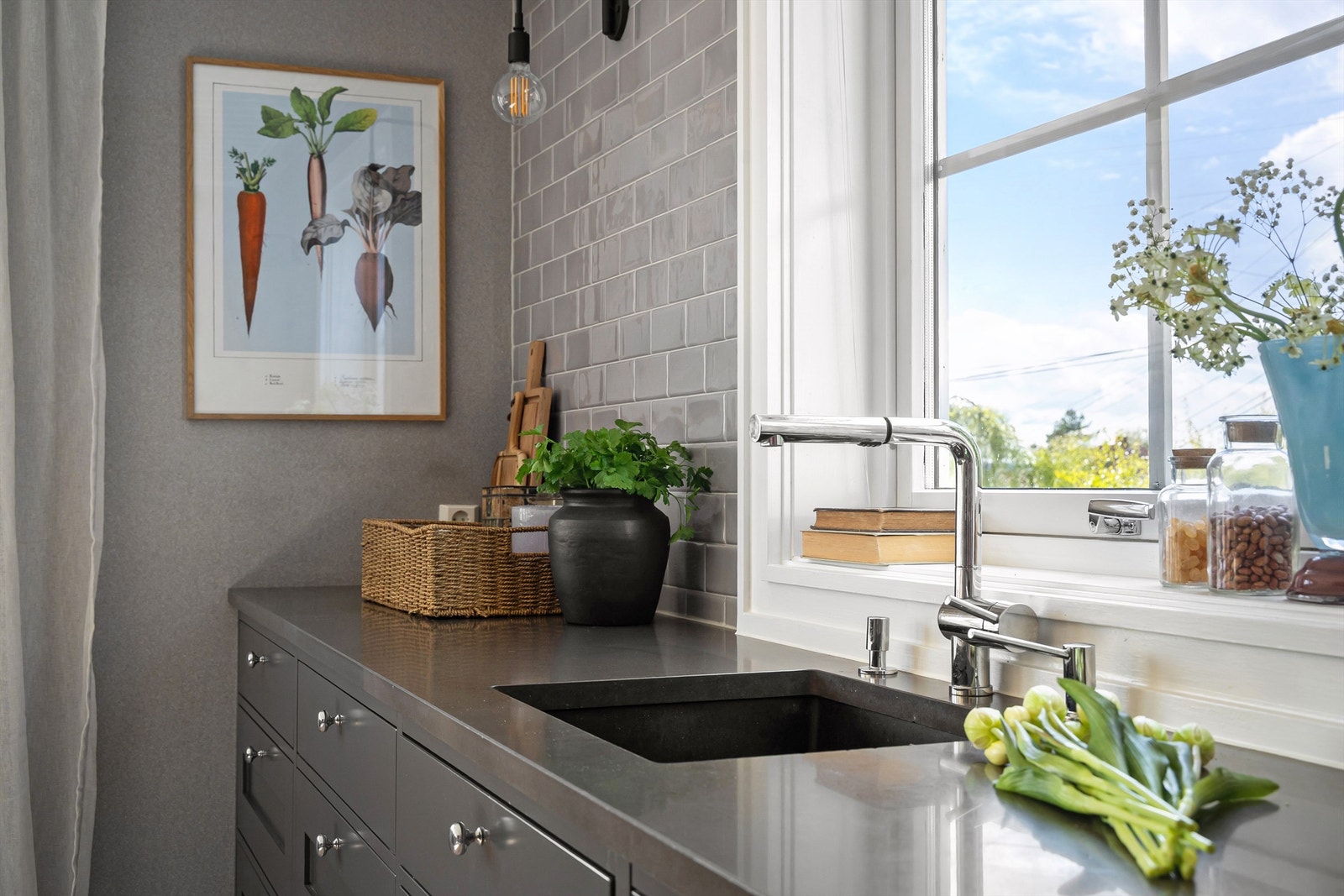 Mørke grå, profilerte fronter og 30 mm benkeplate i stein av type Marengo Silestone med integrerte elsøyler Galleribilde