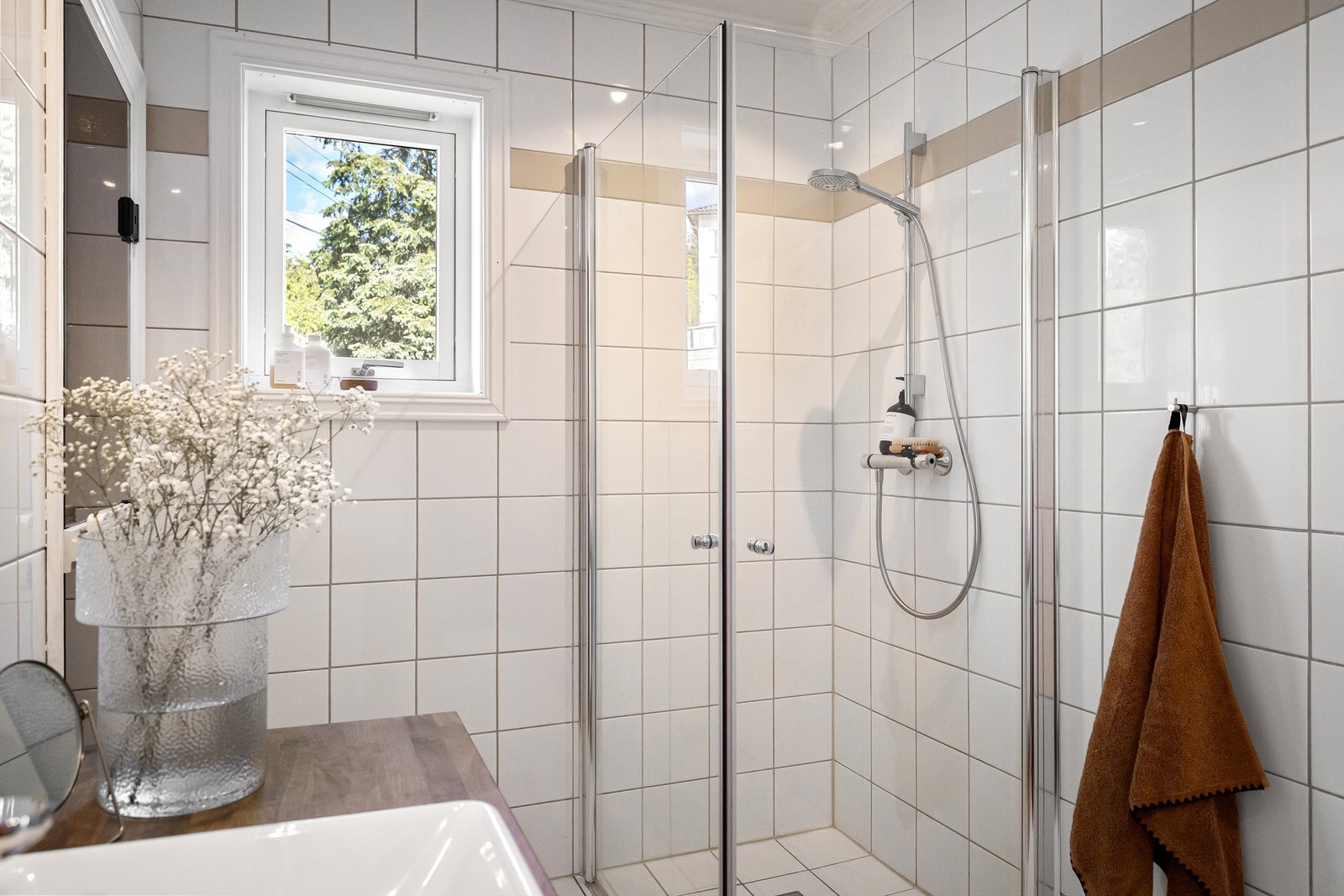 Badet er utstyrt med vegghengt toalett og dusjhjørne med innfellbare glassdører Galleribilde