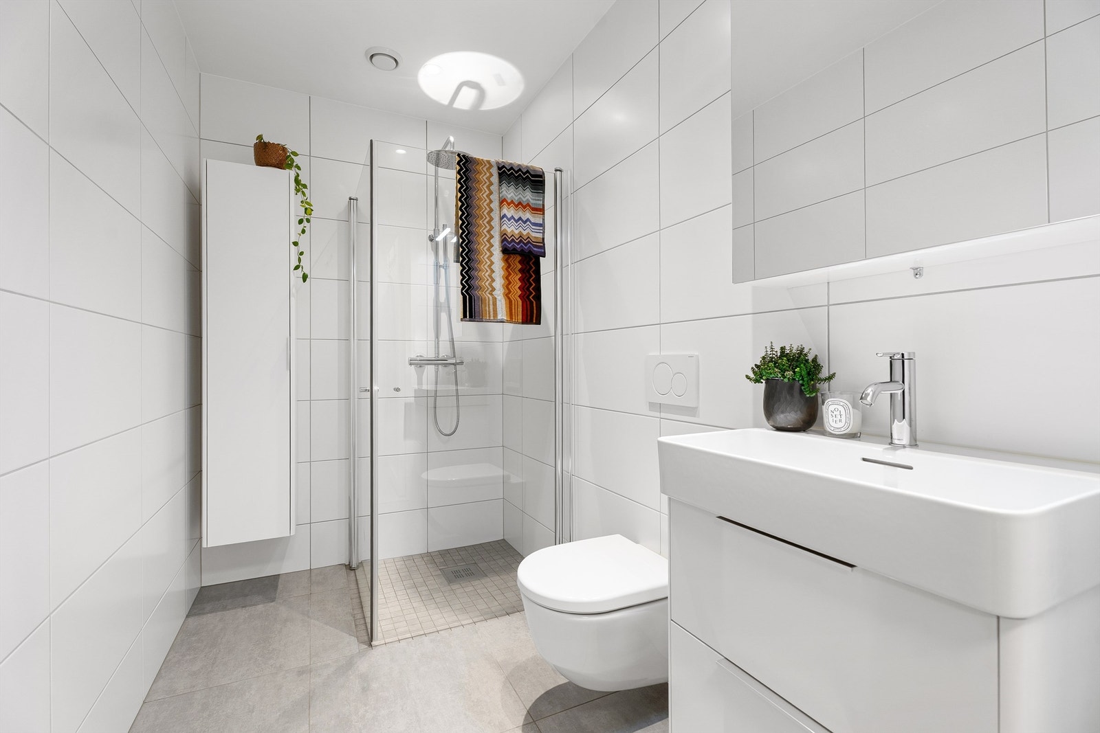 Badet har en tidløs og moderne stil og byr på blant annet dusjnisje med innfellbare dører og regndusj. Det er også baderomsinnredning med plass til ekstra oppbevaring. Galleribilde