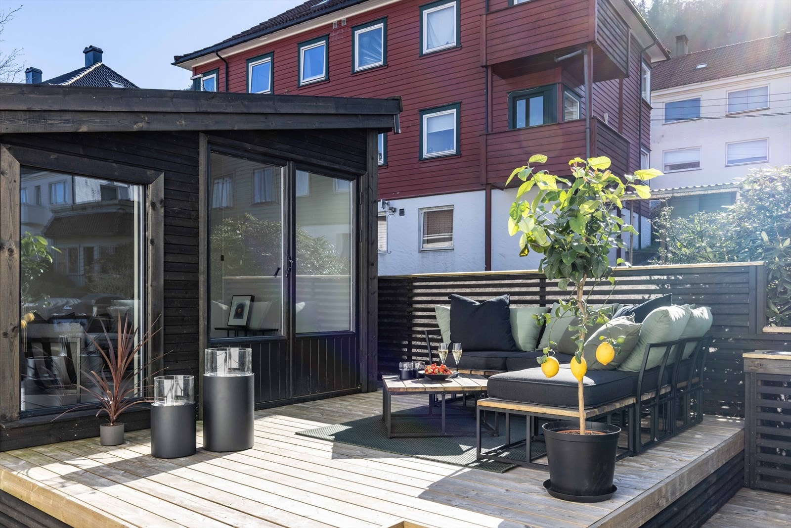 Den ene sonen er innredet som spiseplass med benk og praktisk løsning som benyttes som utekjøkken, mens det andre platået er etablert som et hyggelig lounge område med sofagruppe Galleribilde