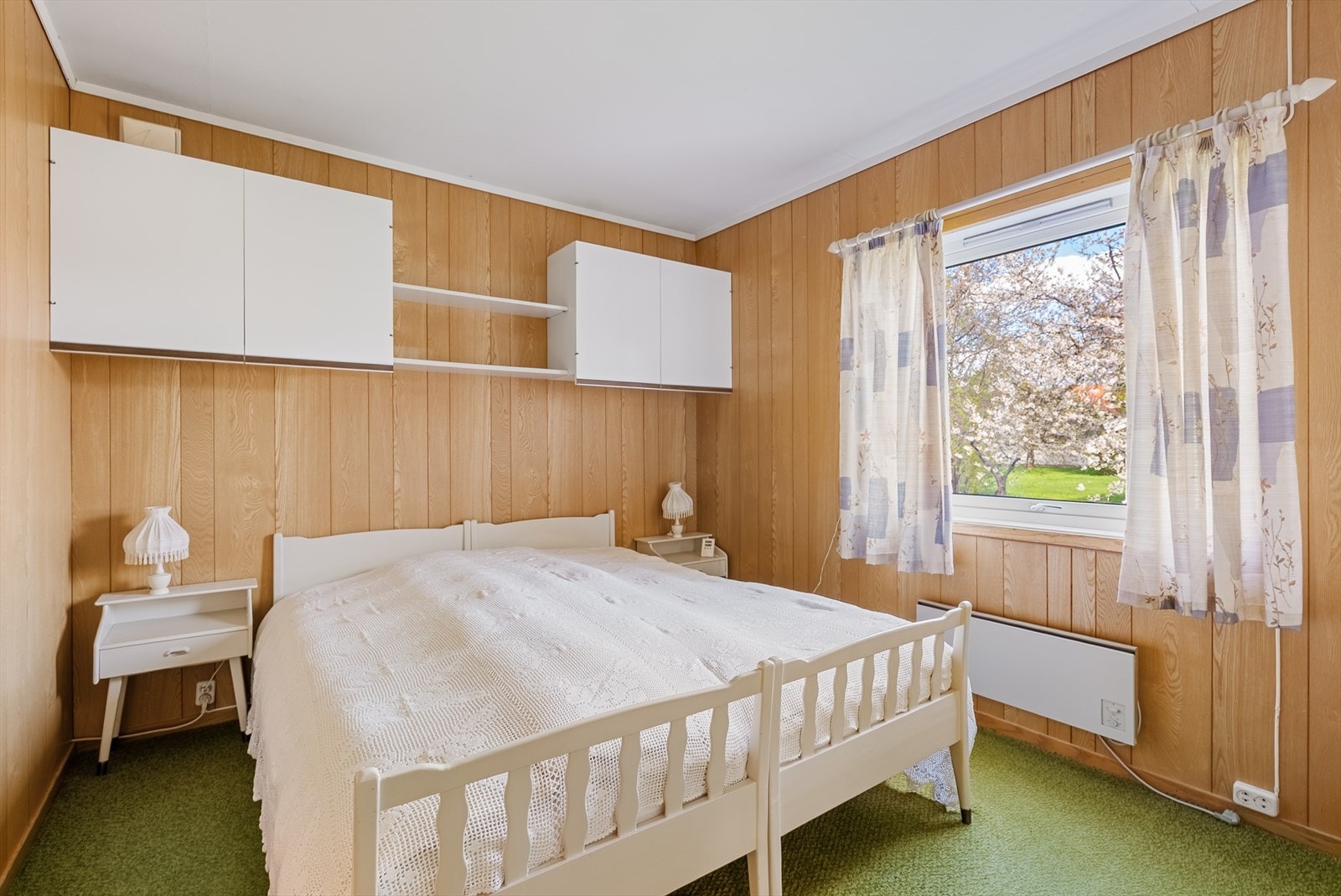 Ett av tre soverom i første etasje, med vegg-til-vegg-teppe og trepanel på veggene. Galleribilde