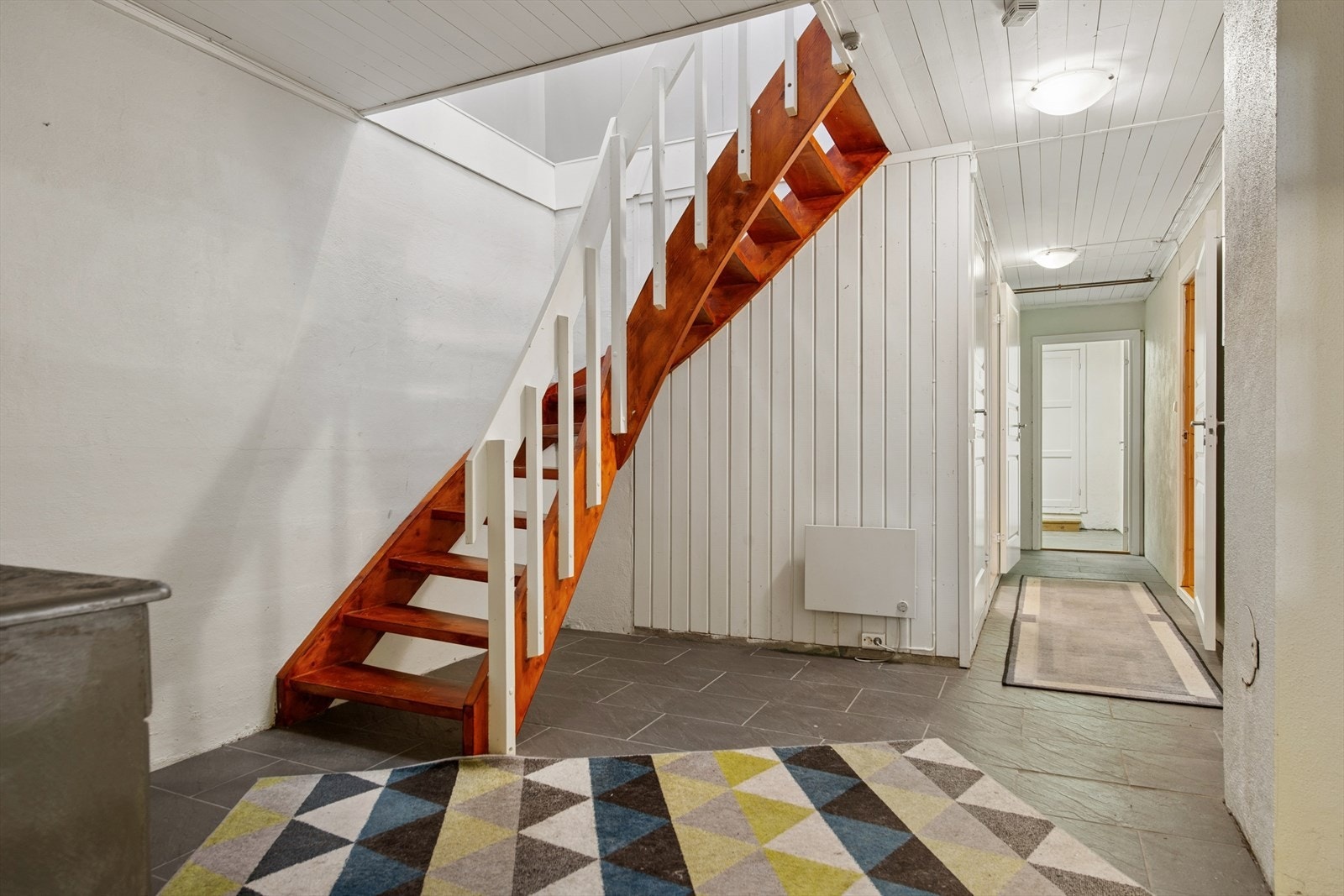 En lakkert tretrapp forbinder de to etasjene. Kjelleren har også egen utvendig adkomst. Galleribilde