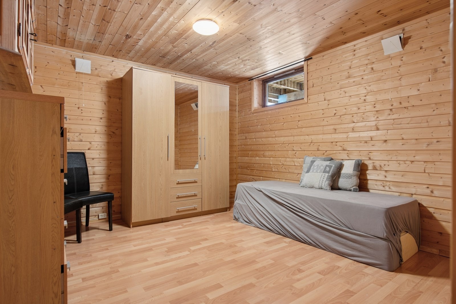 Bodrom i kjelleren med laminatgulv og trepanel på vegger og i himling. Rommet er ikke godkjent som varig oppholdsrom. Galleribilde