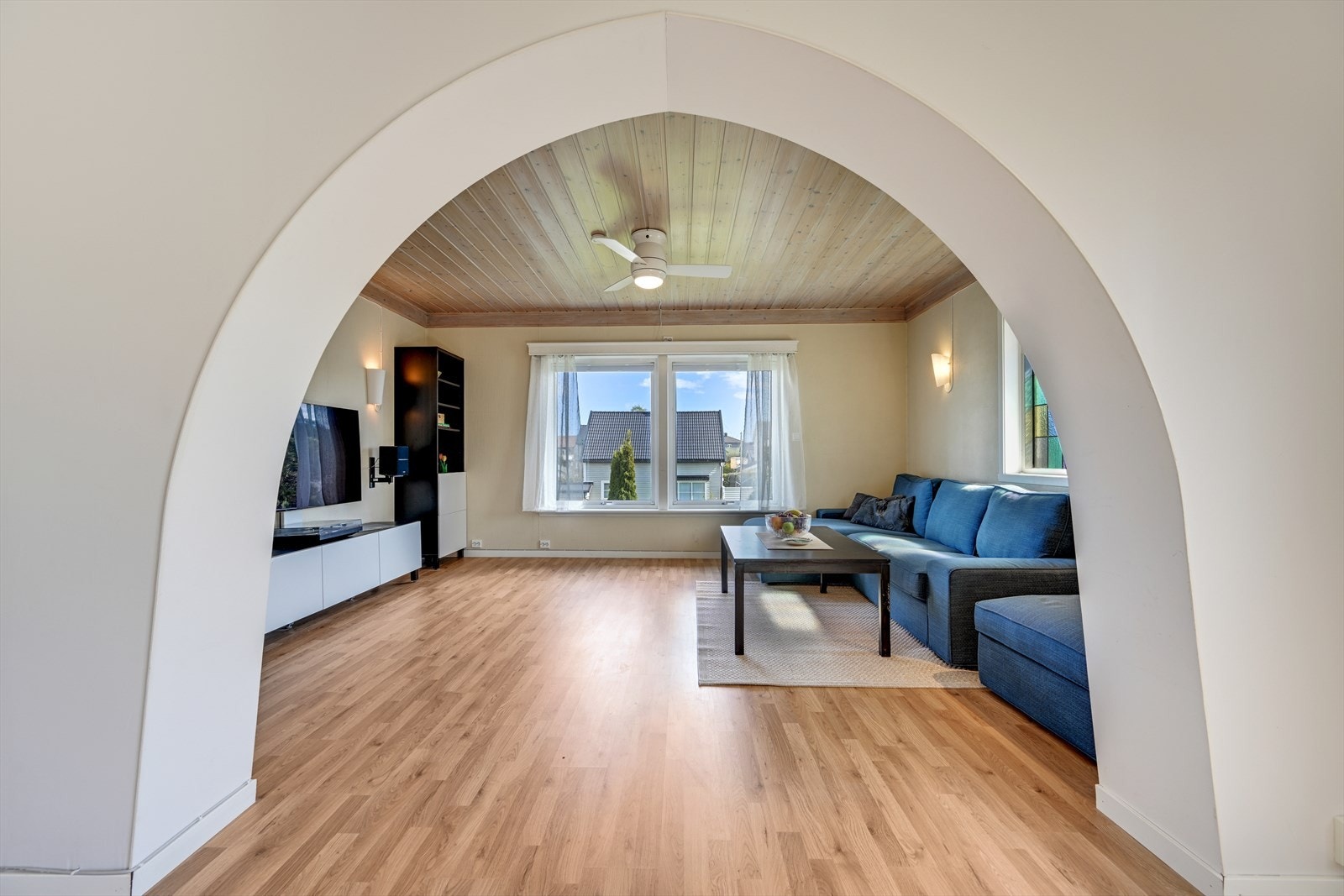 En elegant bueåpning skiller de to stuedelene og skaper en definert, men åpen romfølelse. Galleribilde