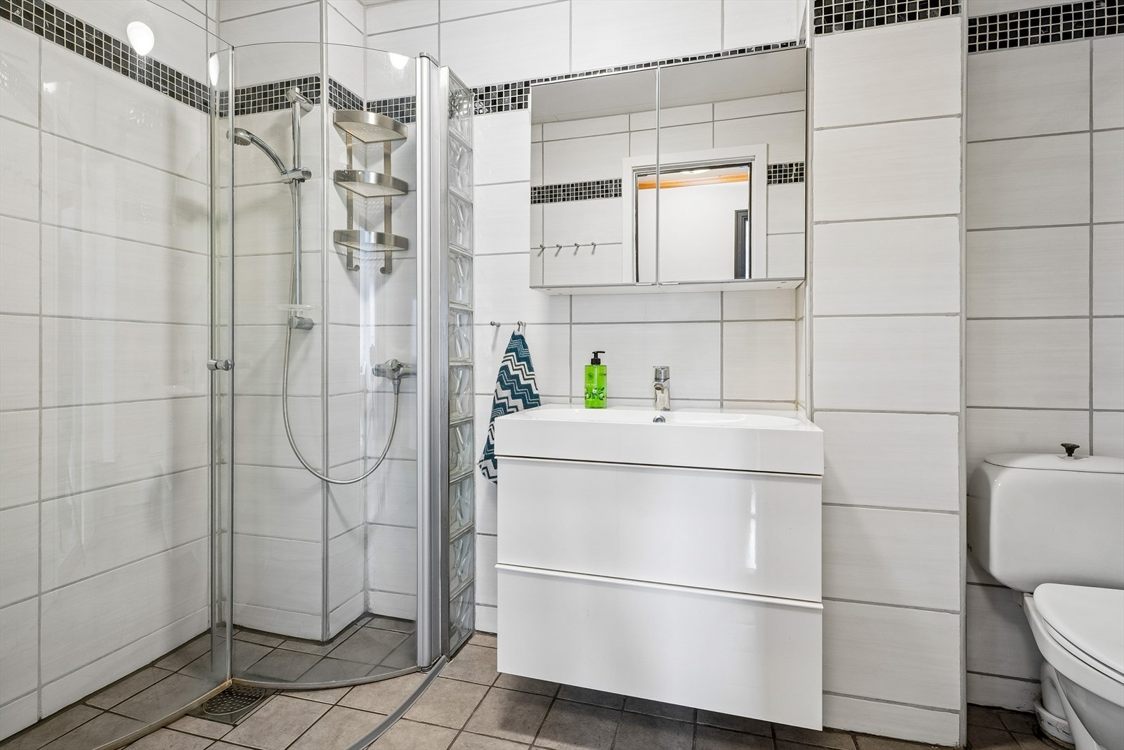 Badet ligg fint samla ved soveromma og er lyst og trivleg bad med dusj på vegg med innfellbare dusjveggar, wc, heildekkande servant og godt med oppbevaring i under og overskap, samt høgskap. Galleribilde