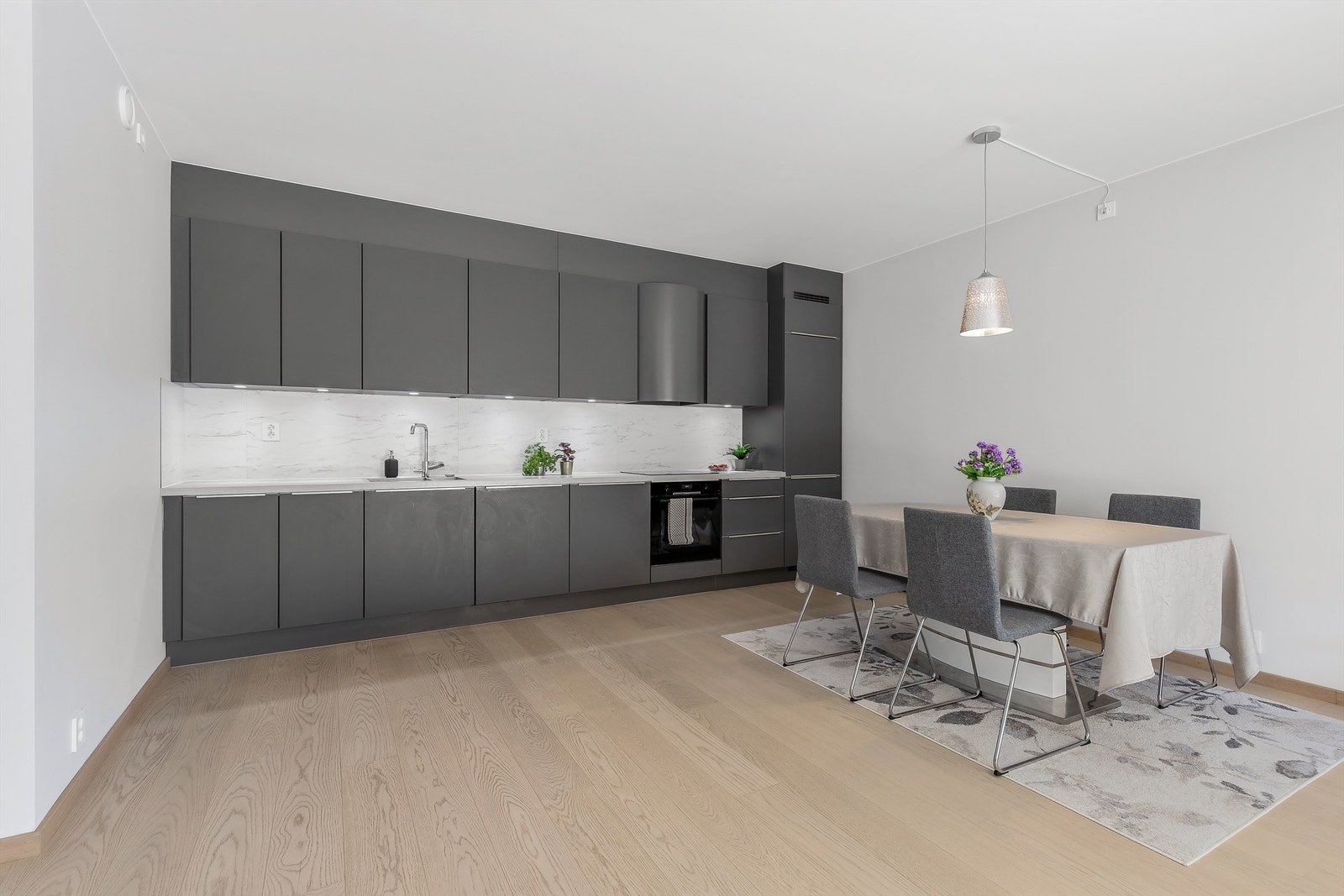 Åpen kjøkkenløsning. Innredning fra byggeår. Glatte fronter. Benkeplate med laminert overflate. Kjøkkenvask med armatur. Integrert stekeovn, platetopp, oppvaskmaskin og kjøleskap med fryser. Galleribilde