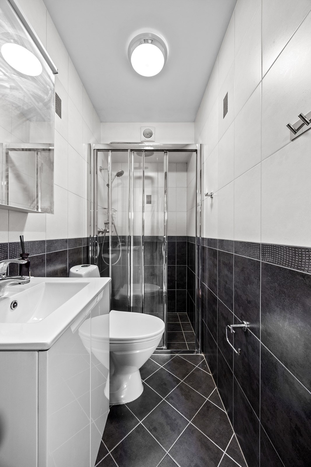 Badet er utstyrt med innredning med porselenservant, gulvmontert toalett og dusjnisje med glassvegg. Galleribilde