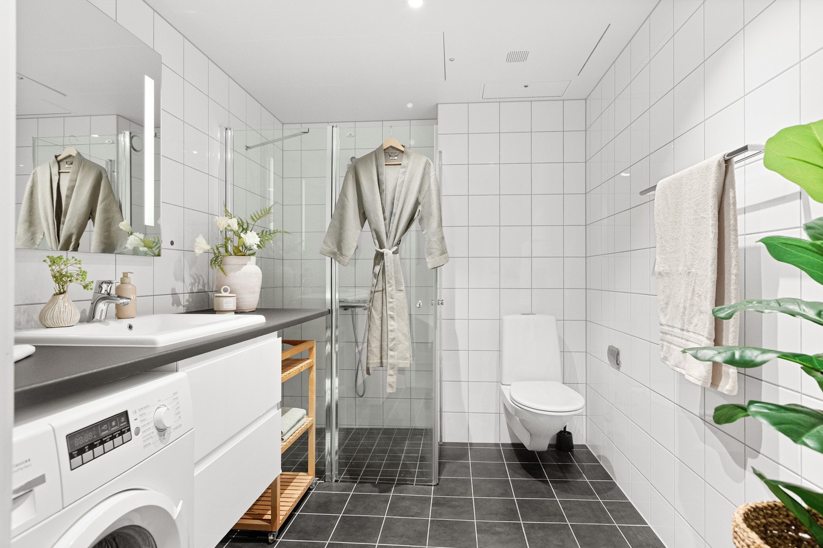 Lyst flislagt baderom med varmekabler i gulv og downlights i himling Galleribilde