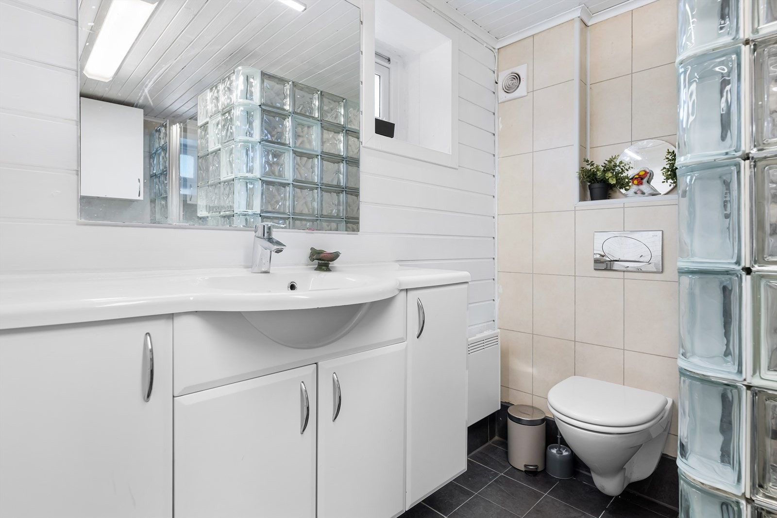 Badet er pent og utstyrt med vegghengt wc, servantinnredning med skap samt dusjrom. Galleribilde