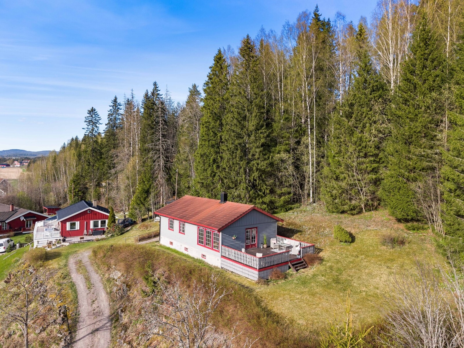 Eiendommen grenser til skogen. Verandaen har plass til flere sittegrupper, solsenger og grill. Galleribilde