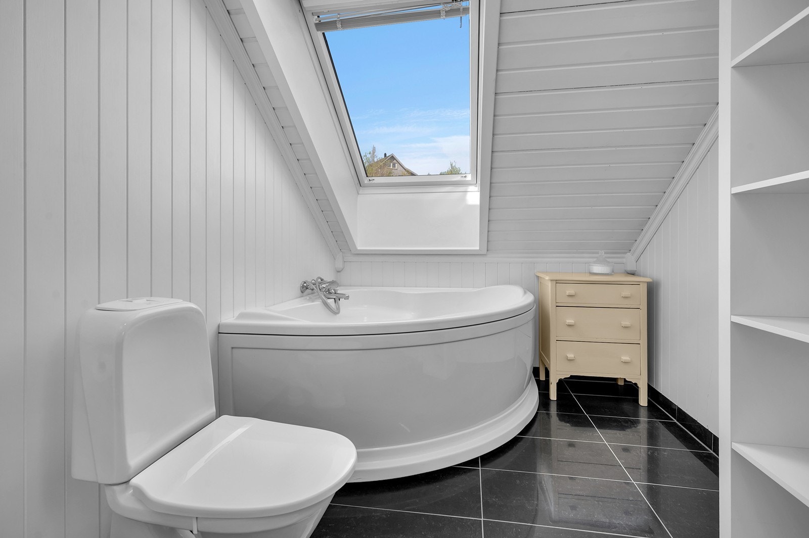 Badet på loftet har fliser på gulv og malte plater på vegger. Galleribilde