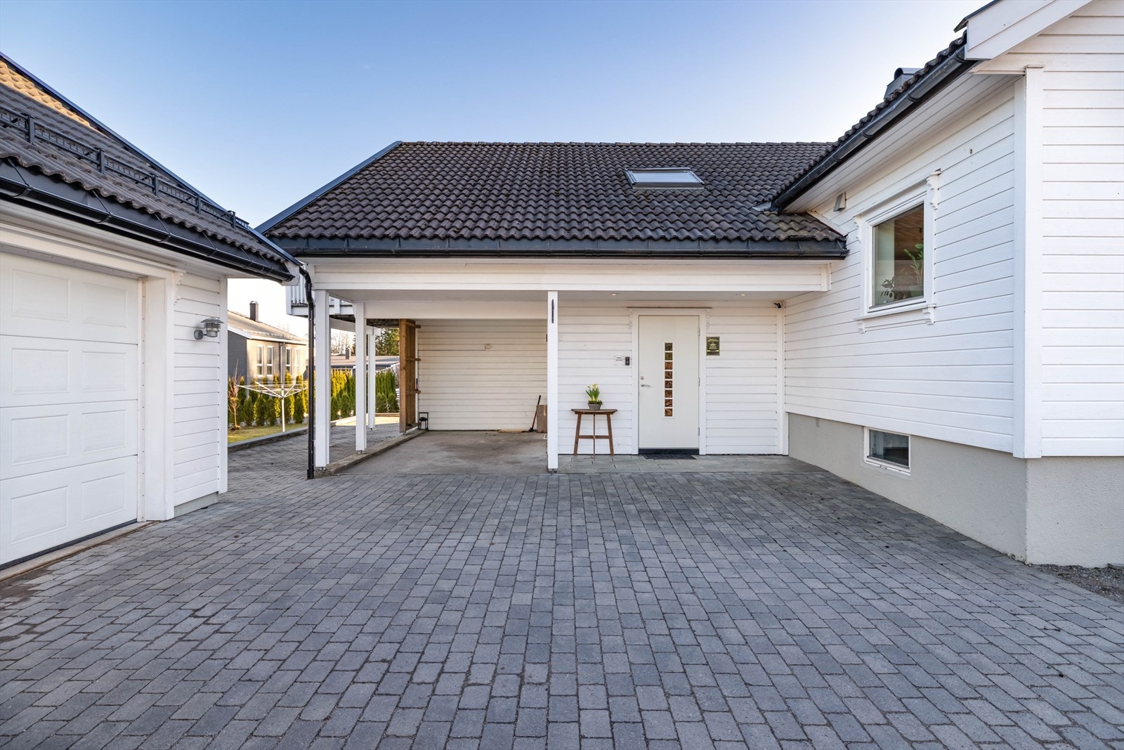 Gårdsplassen er pent opparbeidet med belegningsstein og har carport i tillegg til garasjen. Galleribilde