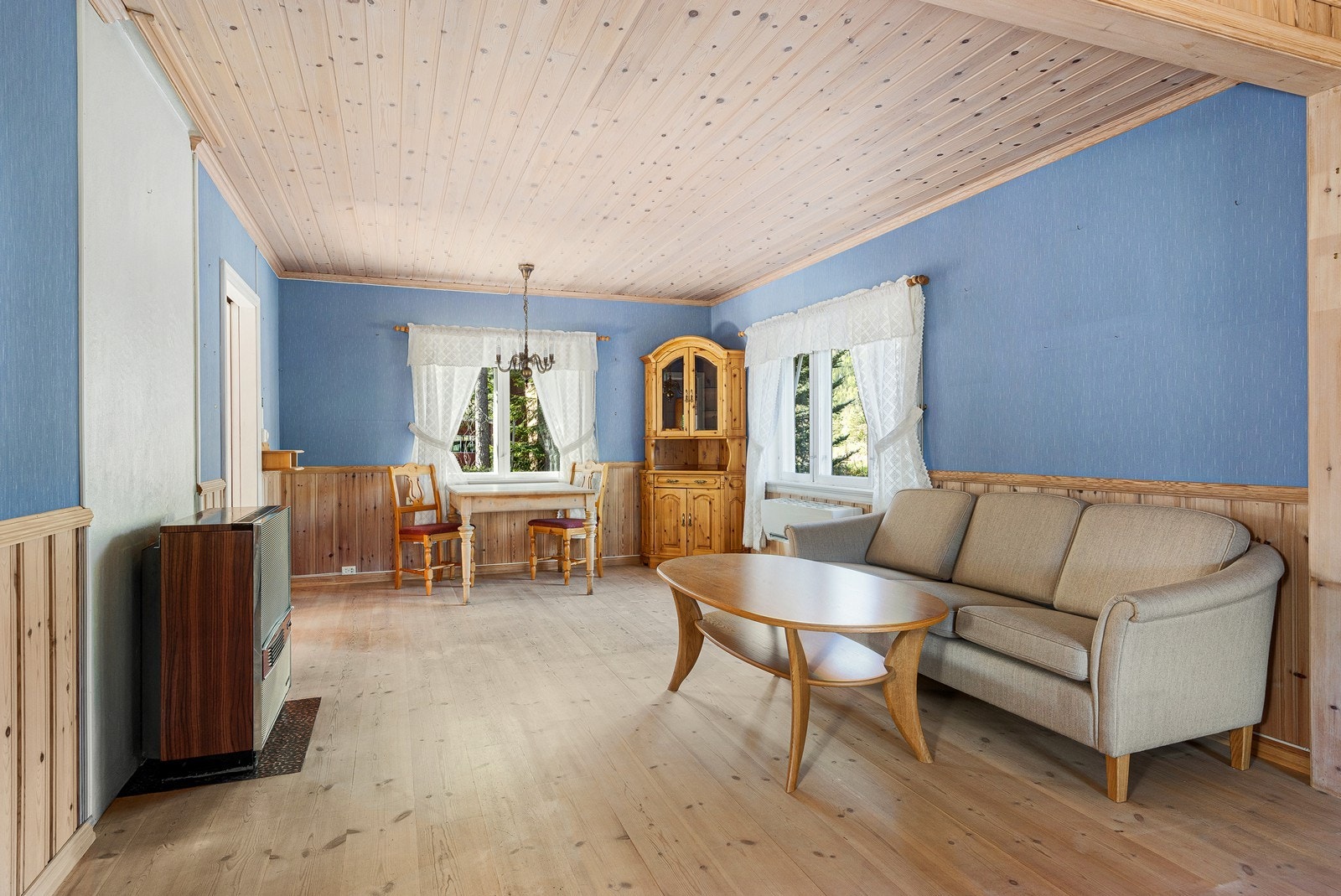Overflatene i stuen består av parkett på gulv, og en kombinasjon av tapet og trepanel på veggene. Galleribilde