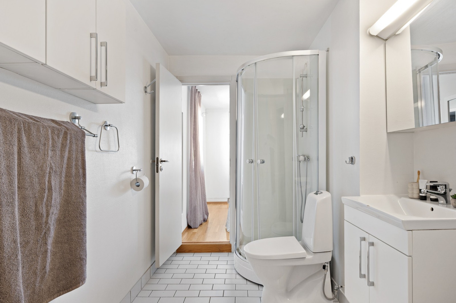 Badet har vegghengt servantinnredning med ovenpåliggende servant, speilskap med overlys og dusjkabinett. Det er også opplegg for vaskemaskin. Galleribilde
