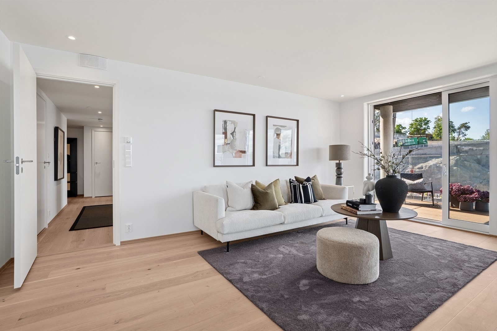 I stuen er det fin plass til en sofagruppe med TV-løsning og et spisebord mot kjøkkenet. Blinds på de store vinduene mot terrassen sørger for å dempe sollyset på de varmeste dagene. Galleribilde