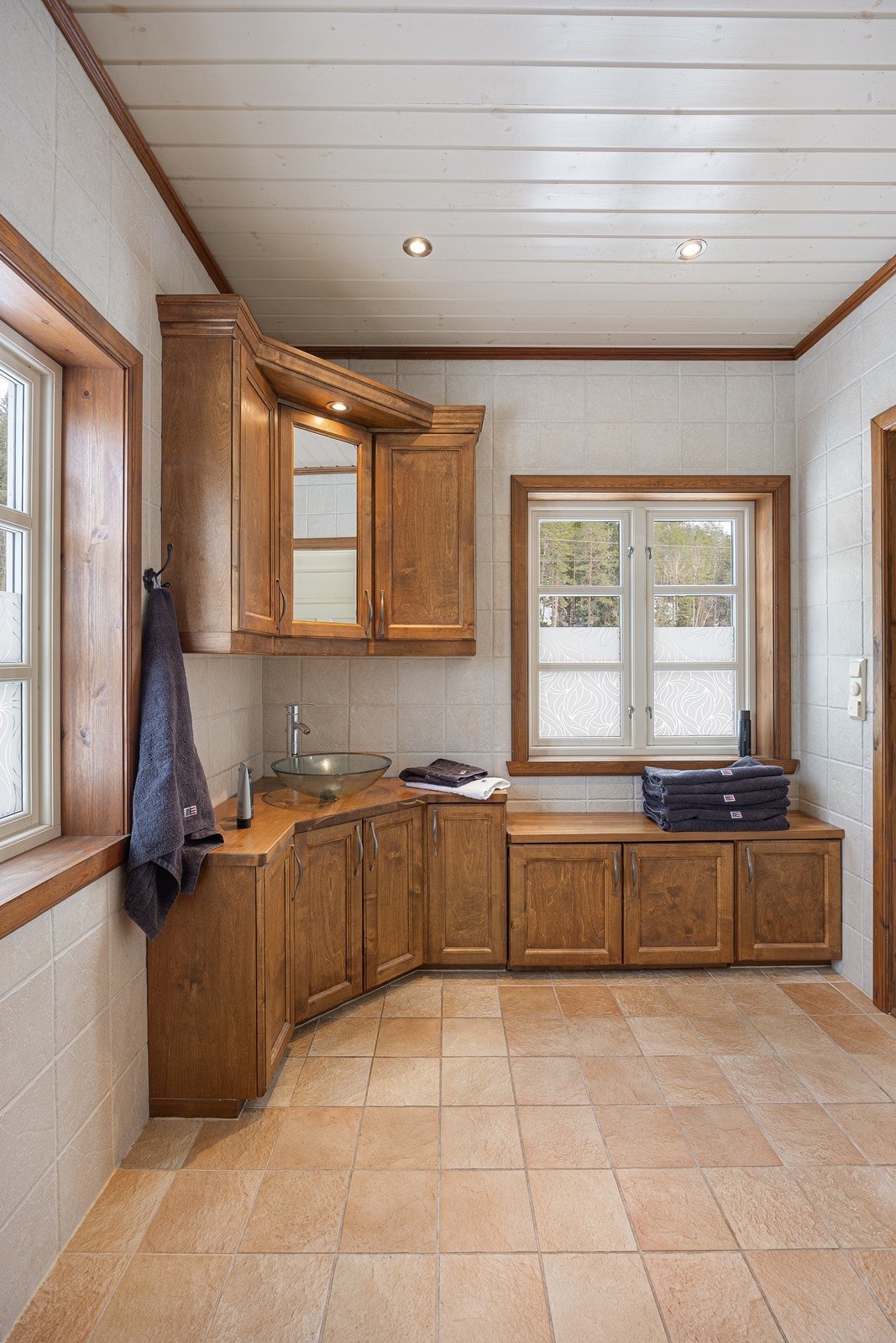 Badet fremstår som romslig, pent og velholdt, og har lyse fliser på veggene, downlights i himlingen og beige fliser på gulv med gulvvarme. Galleribilde