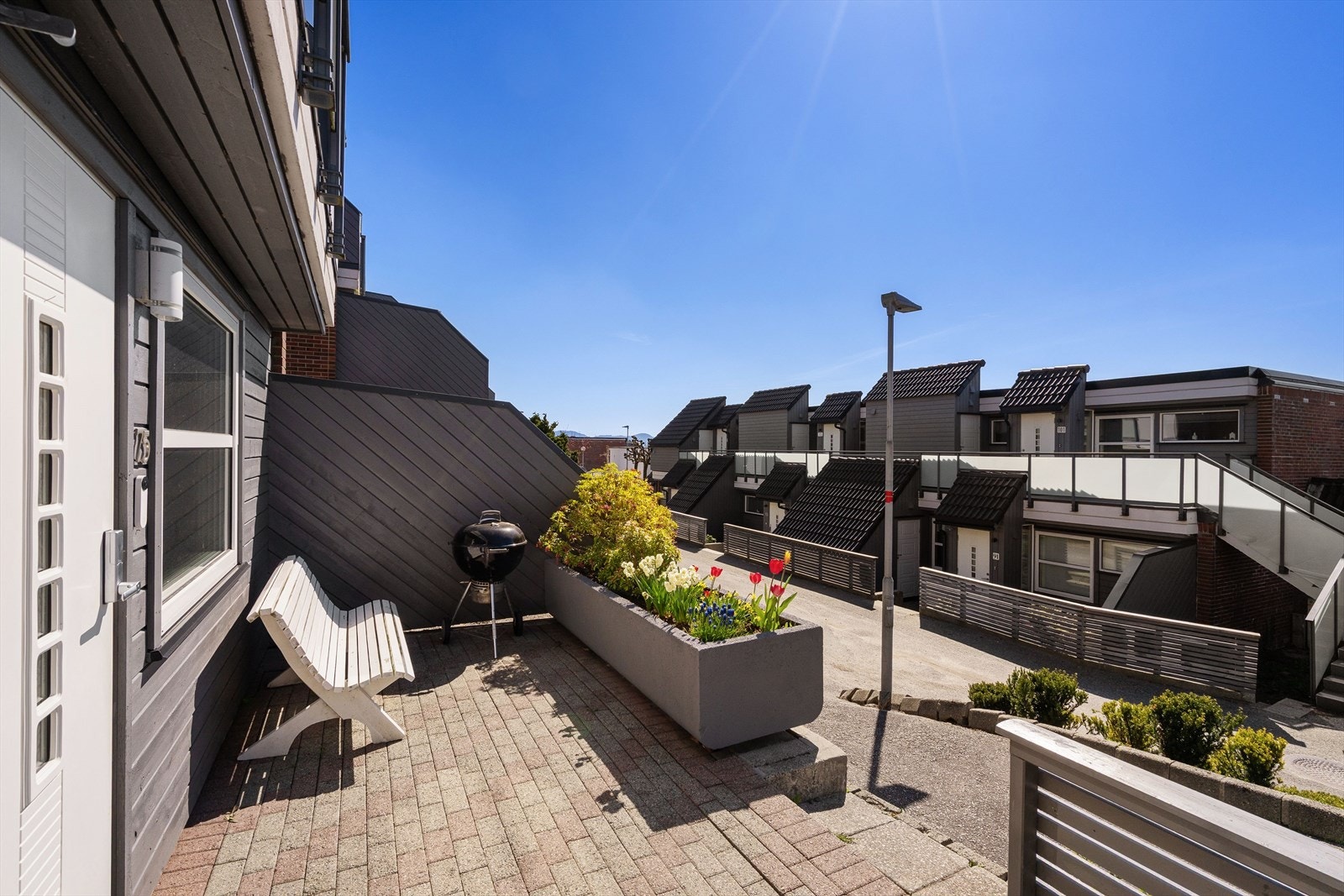 Du disponerer også en pent opparbeidet markterrasse med belegningsstein, supplert med dekorative blomsterkasser som bidrar til et helhetlig og innbydende uteområde. Galleribilde