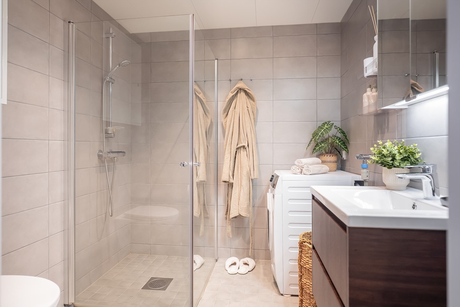 Badet er innredet med dusjhjørne, vegghengt toalett, speilskap, servant med gode oppbevaringsmuligheter samt opplegg for vaskemaskin. Galleribilde