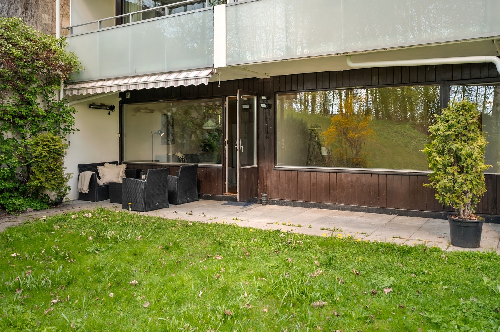 Uteplass med steinheller på ca. 16,3 kvm og hyggelig hage, som fungerer som en naturlig forlengelse av oppholdsrommet i sommerhalvåret Galleribilde