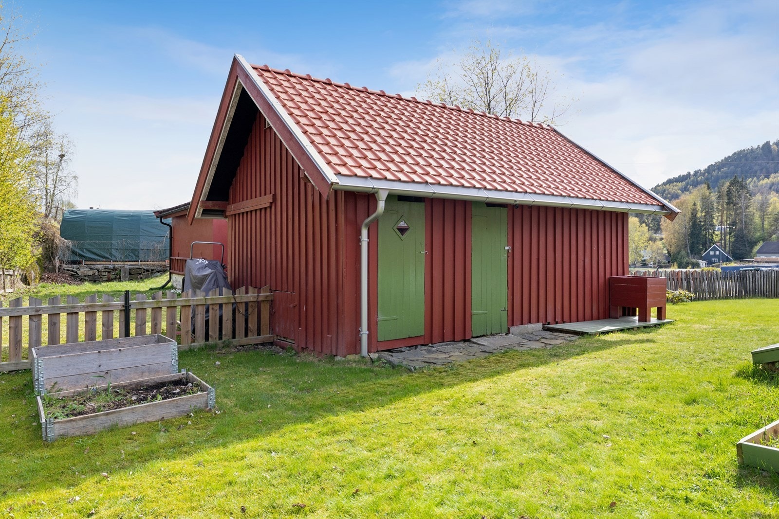 Tomten har inngjerdet hage med plen og variert beplantning. Galleribilde