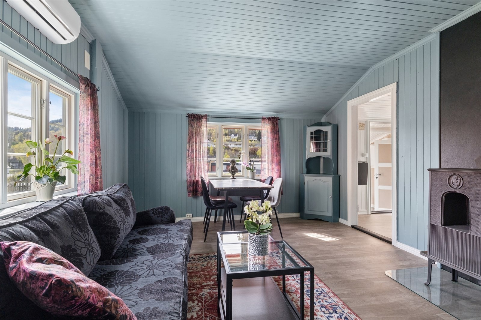 Stuen har plass til sofagruppe og spisebord. Rommet er utstyrt med både varmepumpe og vedovn. Galleribilde