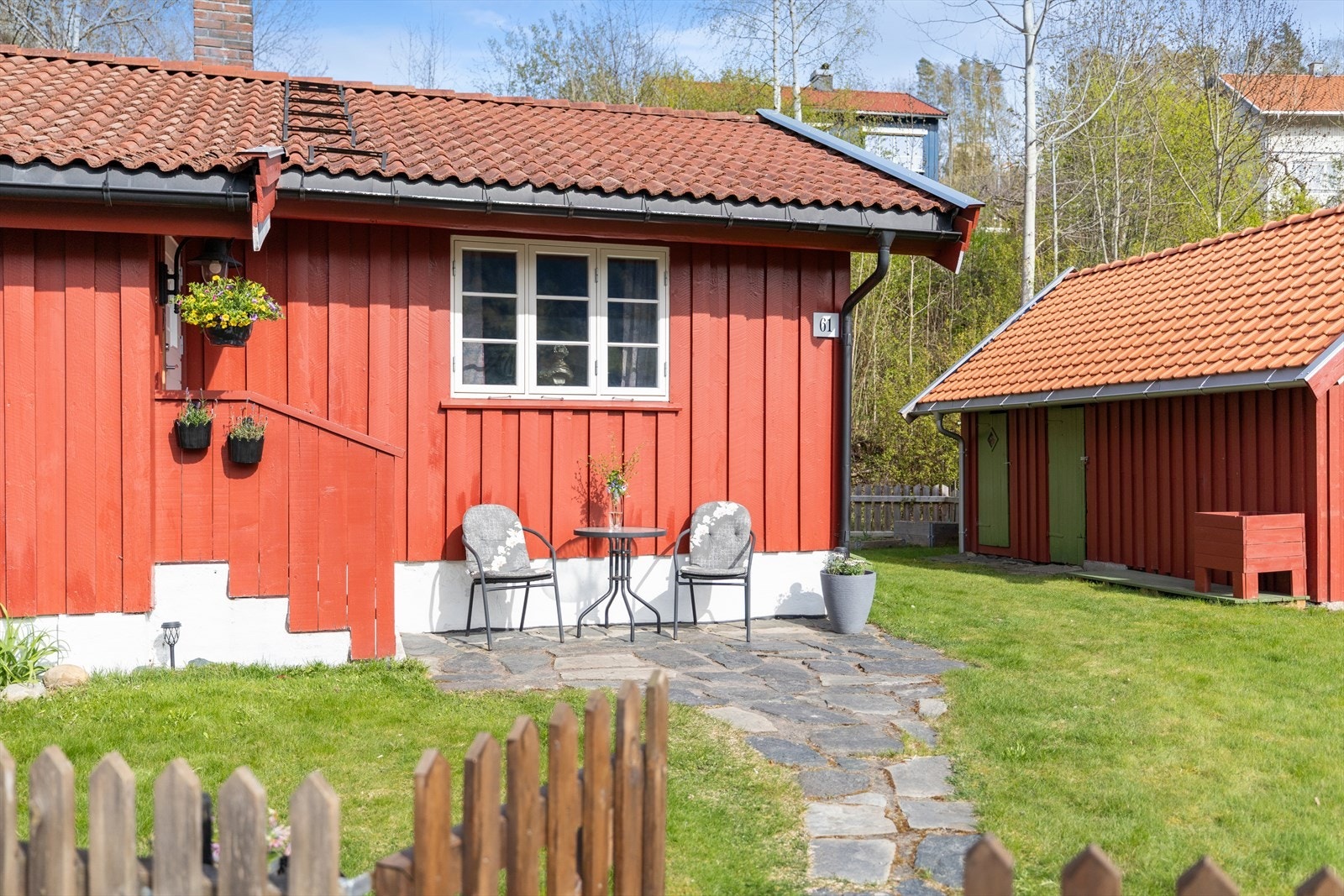 Tomten er flat og pent opparbeidet med plen, beplantinger og hellelagt gangvei. Galleribilde