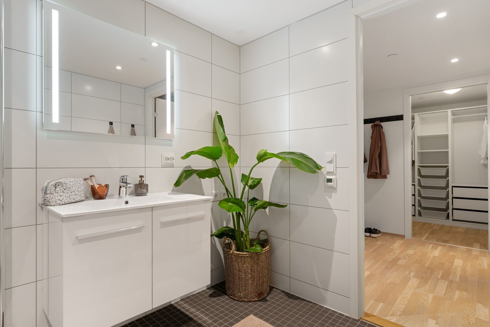 Det 5,5 kvm store badet har flislagte overflater og behagelig gulvvarme. God belysning fra downlights i himling og integrert lys i speil. Galleribilde