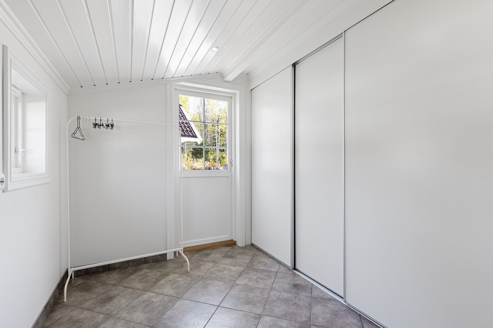 Tilbygget del til vaskerommet med stor garderobe. Utgang til gårdsplassen. Perfekt for tørking, oppbevaring mv. Galleribilde