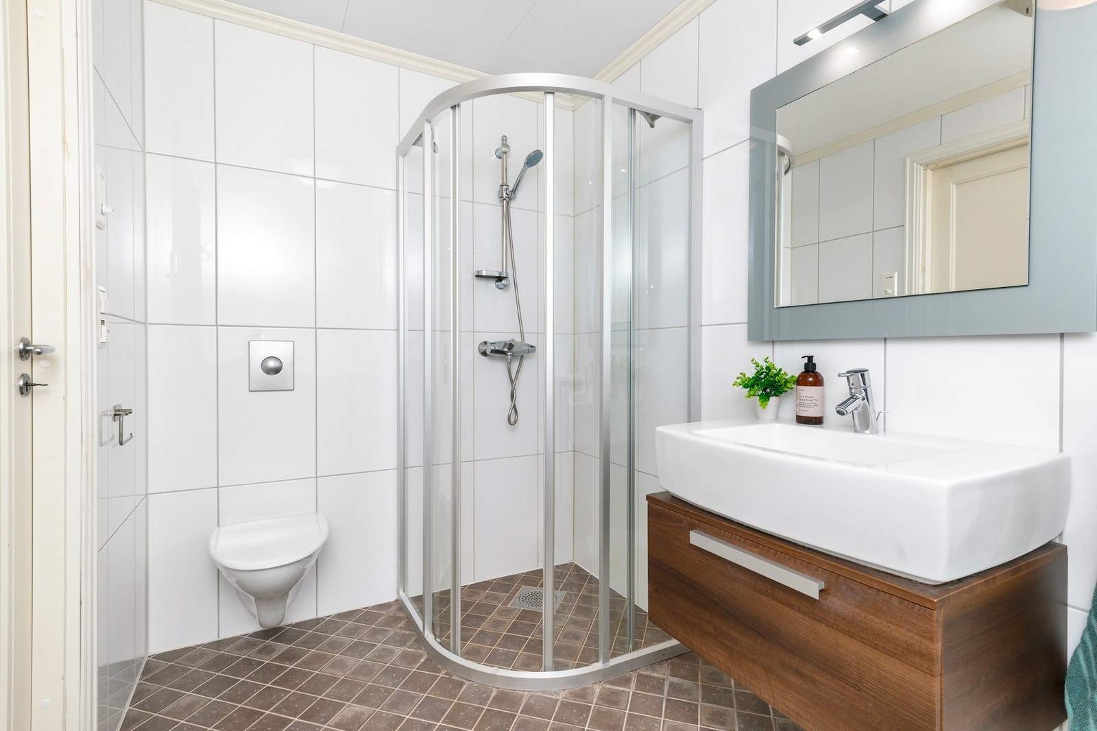 Badet er utstyrt med servantskap, gulvmontert toalett og dusjsone. Galleribilde