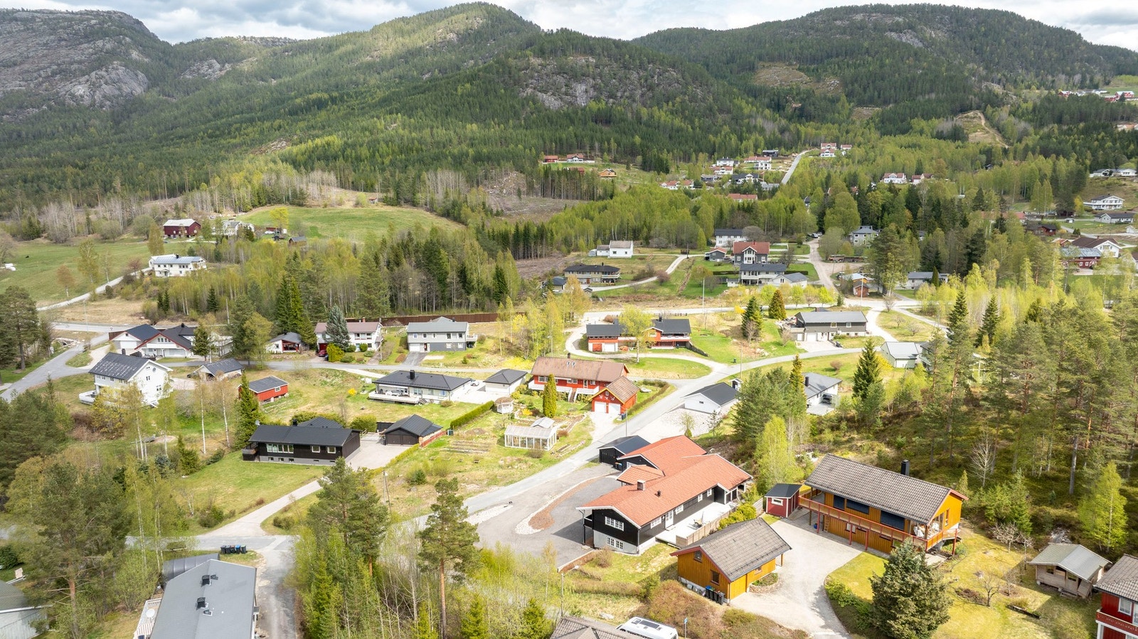 Oversiktsbilde av tomt og bebyggelse, med hovedhus, garasje og uthus i helhetlig stil. Galleribilde