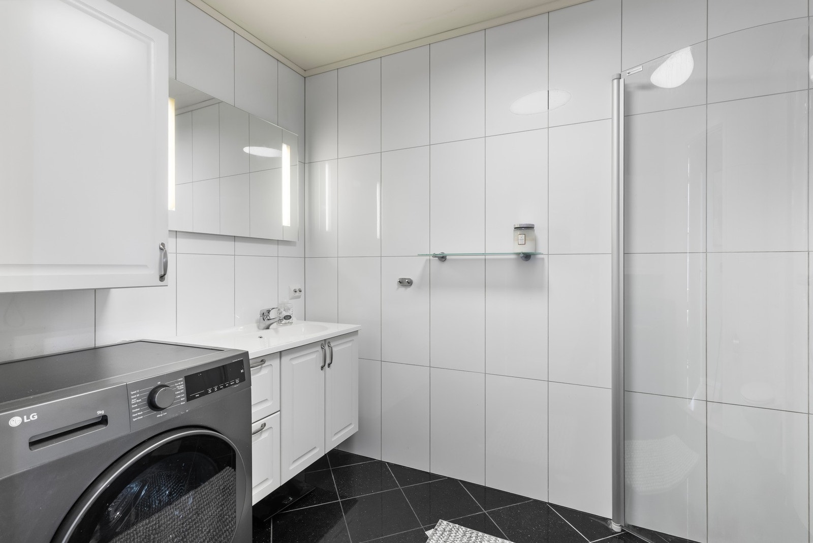 Flislagt bad/vaskerom med varmekabler og opplegg for vaskemaskin. Galleribilde