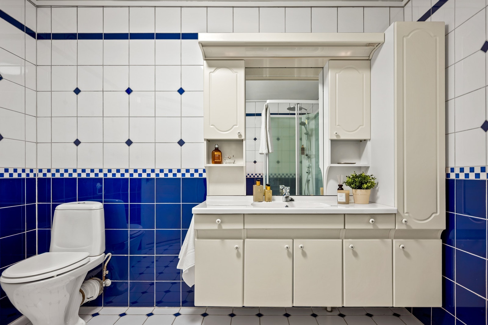 Badet er helfliset og utstyrt med dusjkabinett, toalett og en romslig servantinnredning med speil samt overlys. Galleribilde